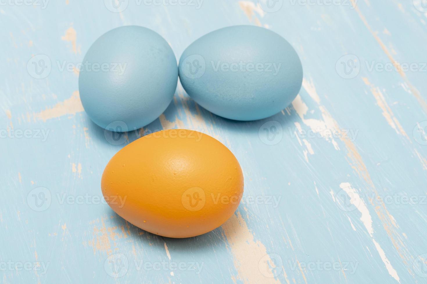 Eggs symbolizing the Easter holiday in blue and orange color on a background of aged wood photo