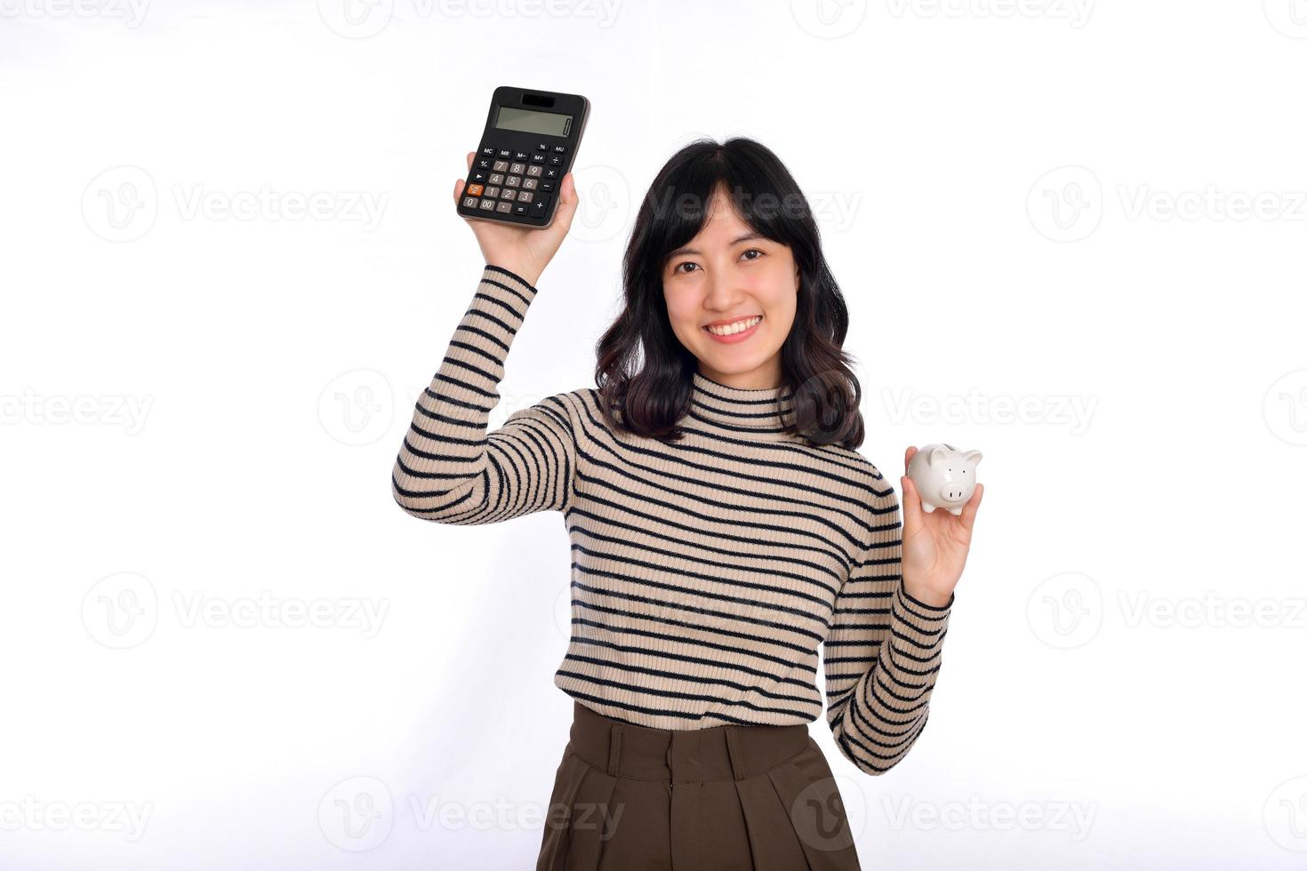 Portrait of young Asian woman casual uniform holding white piggy bank and calculator isolated on white background, Financial and bank saving money concept photo