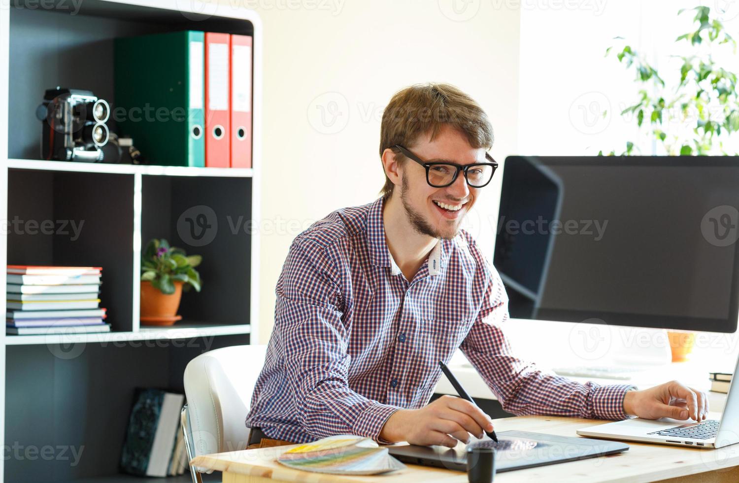 Young artist drawing something on graphic tablet at the home office photo