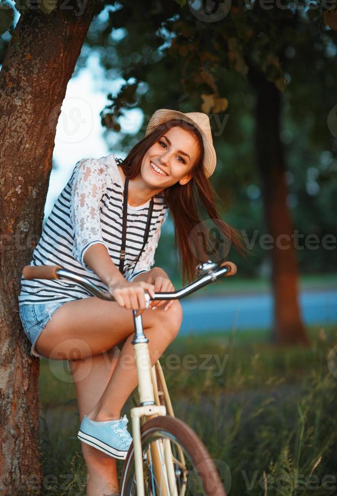 Lovely young woman in a hat with a bicycle outdoors photo
