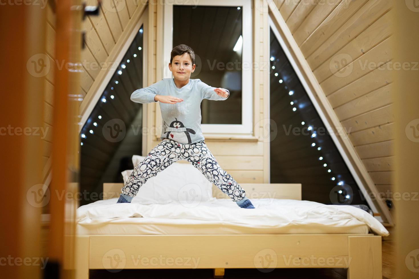 Boy in pajama playing at wooden cabin home. Concept of childhood, leisure activity, happiness. photo