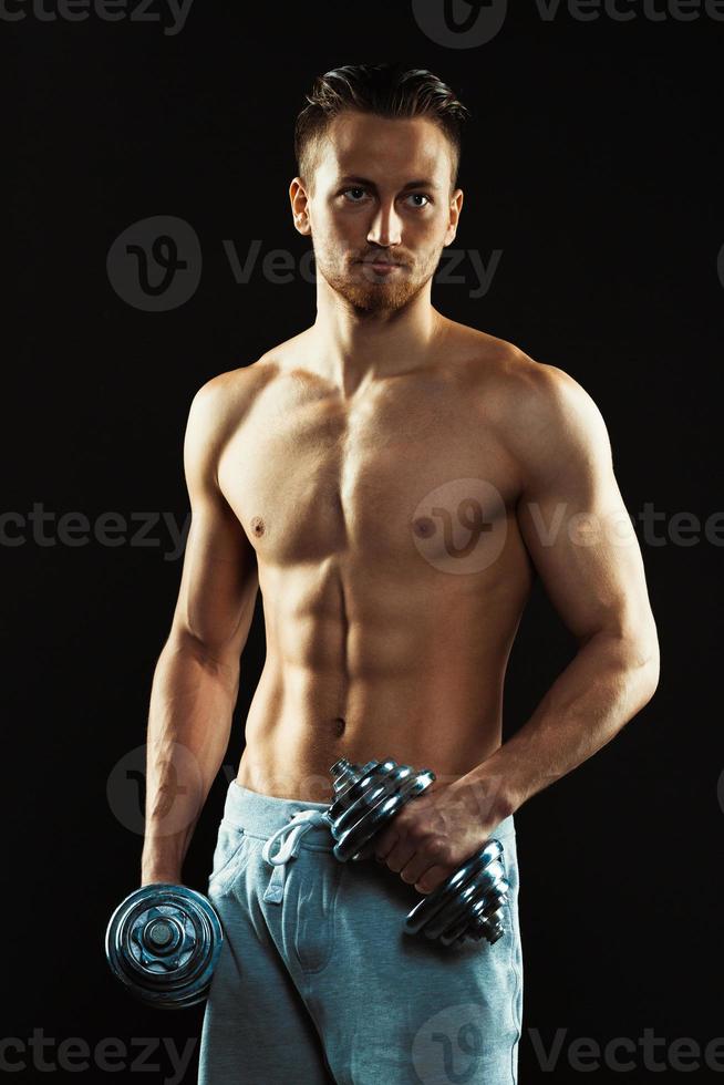 Athletic man with dumbbells on the black background photo