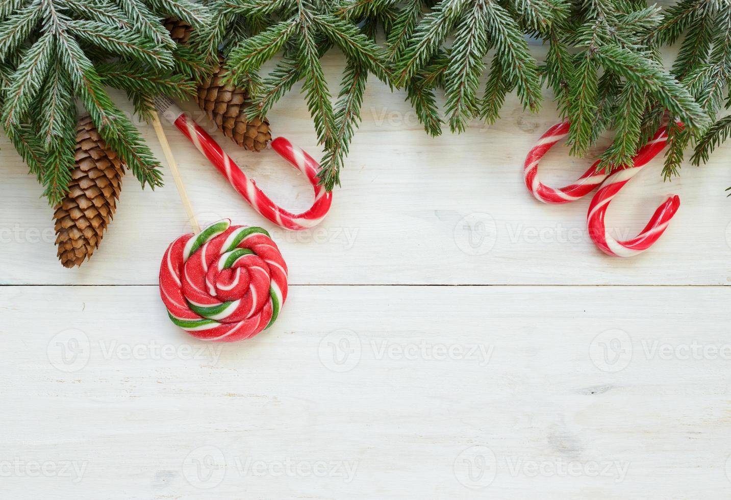 Christmas border with fir tree branches with cones and candy cane on white wooden boards ready photo