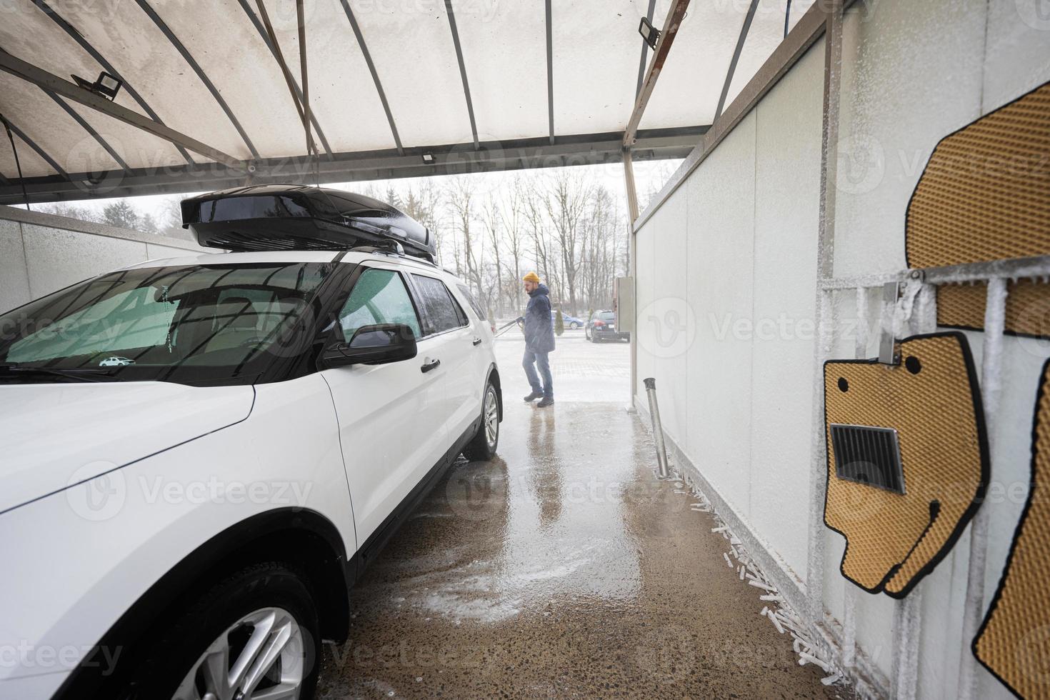 Man washing high pressure water american SUV car with roof rack at self