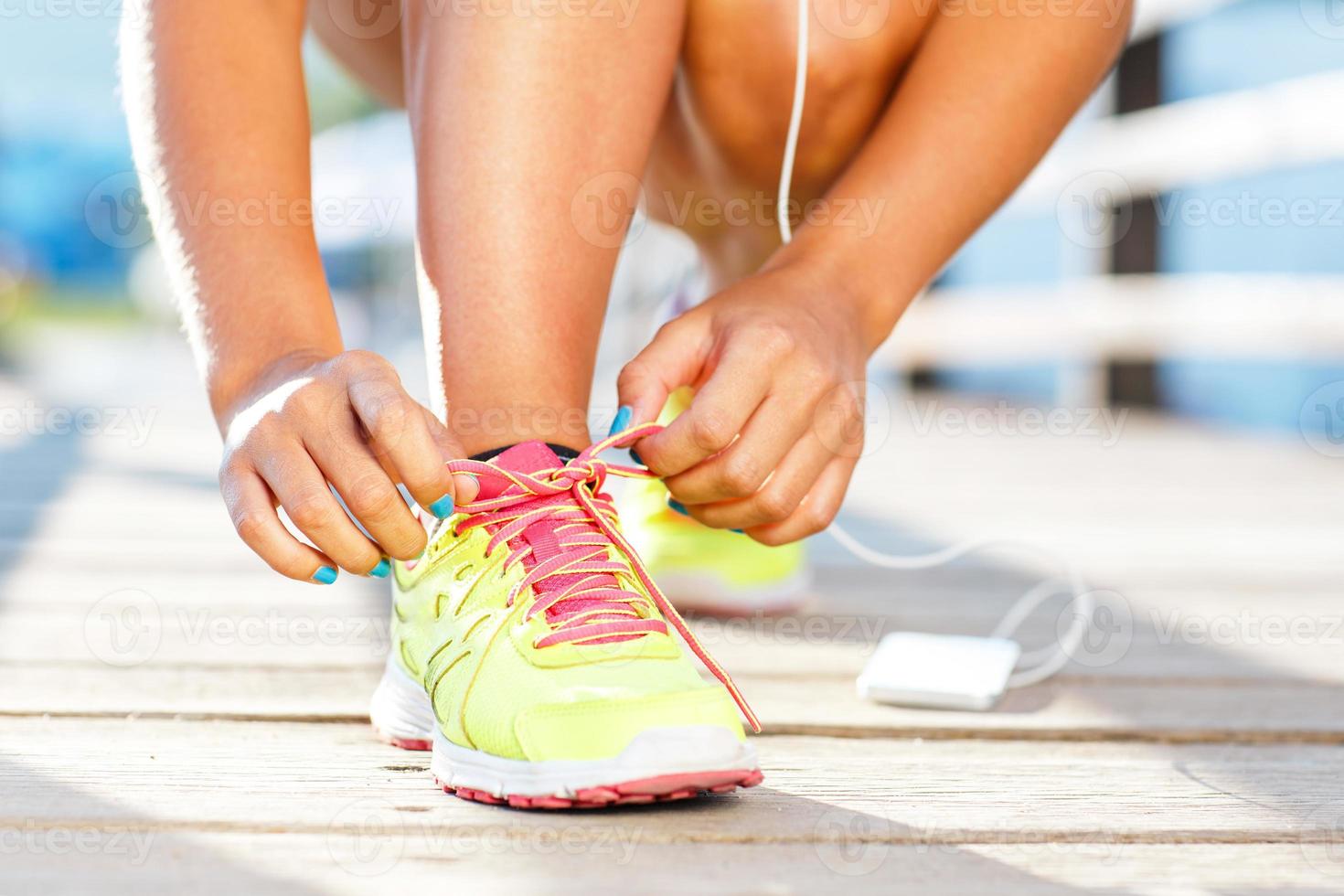 Running shoes - woman tying shoe laces. Closeup of female sport fitness runner getting ready for jogging outdoors photo