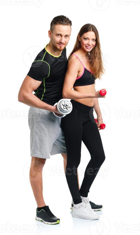 Athletic man and woman with dumbbells on the white photo