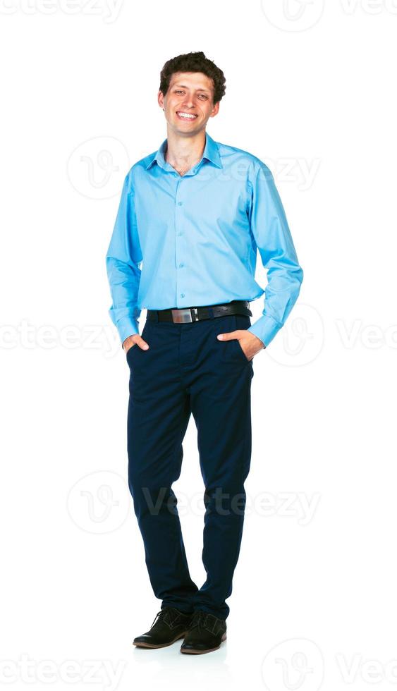 Happy young businessman standing with his hands in pockets on white photo