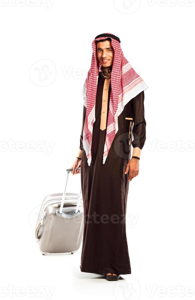 Young smiling arab with a suitcase isolated on white photo