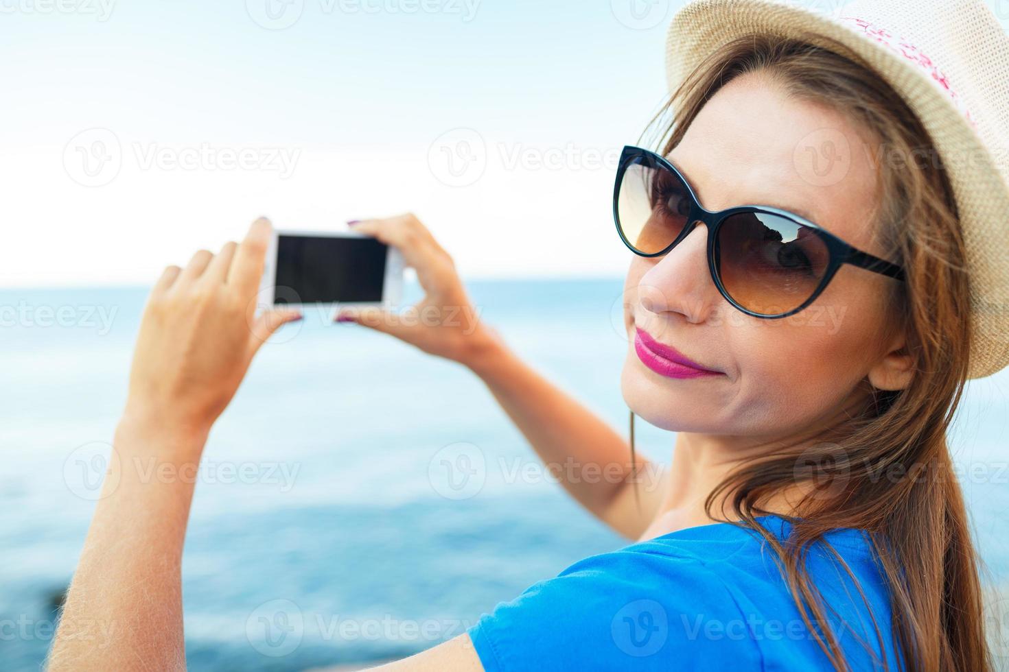 niña en sombrero haciendo fotos de el adriático mar por el teléfono inteligente