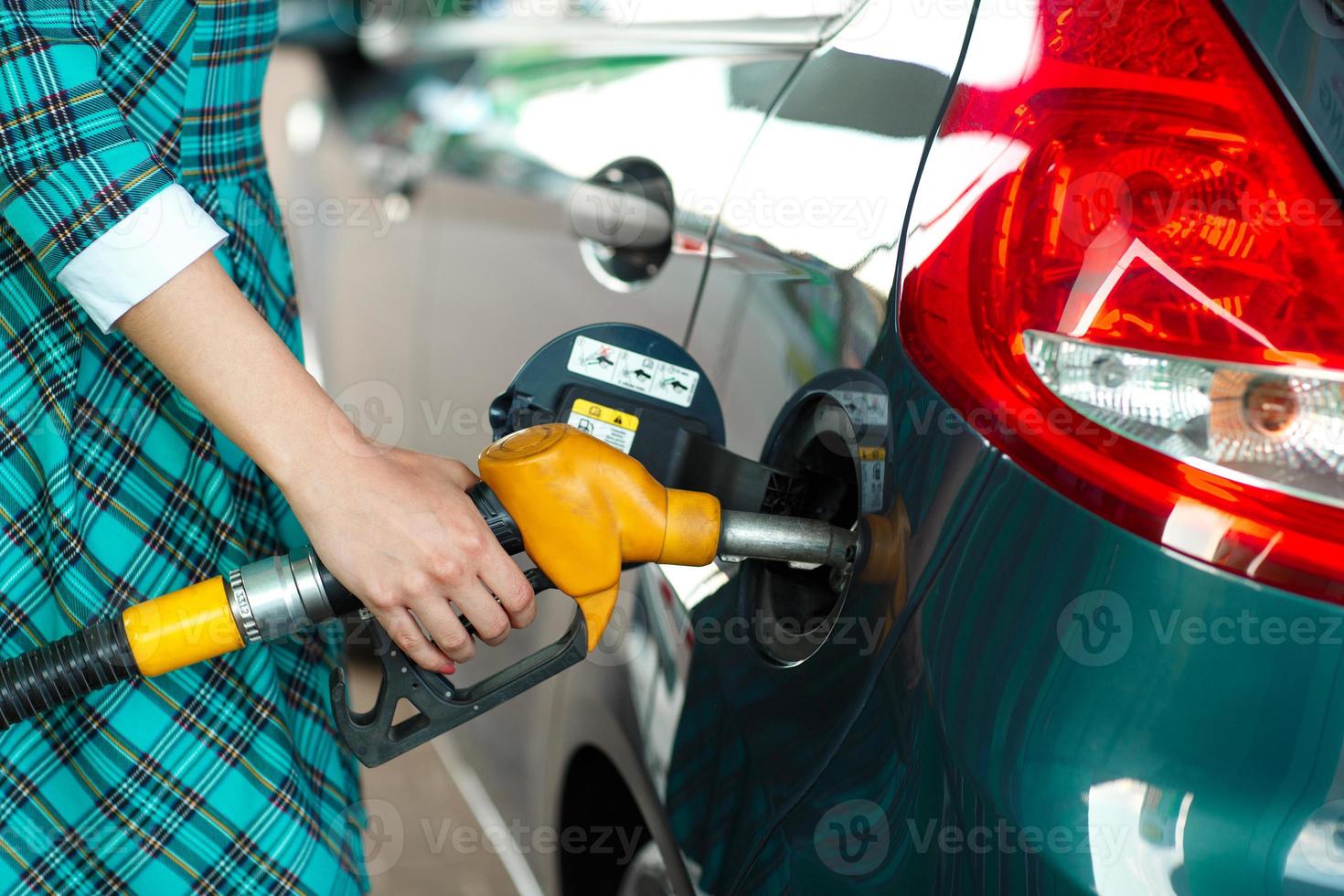 Woman fills petrol into her car at a gas station photo