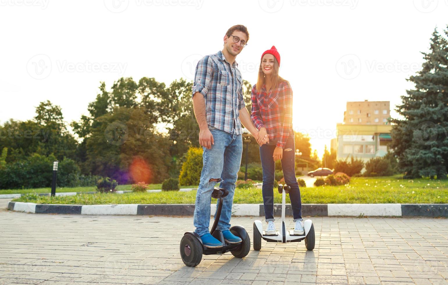 A young couple riding hoverboard - electrical scooter, personal eco transport, gyro scooter, smart balance wheel photo