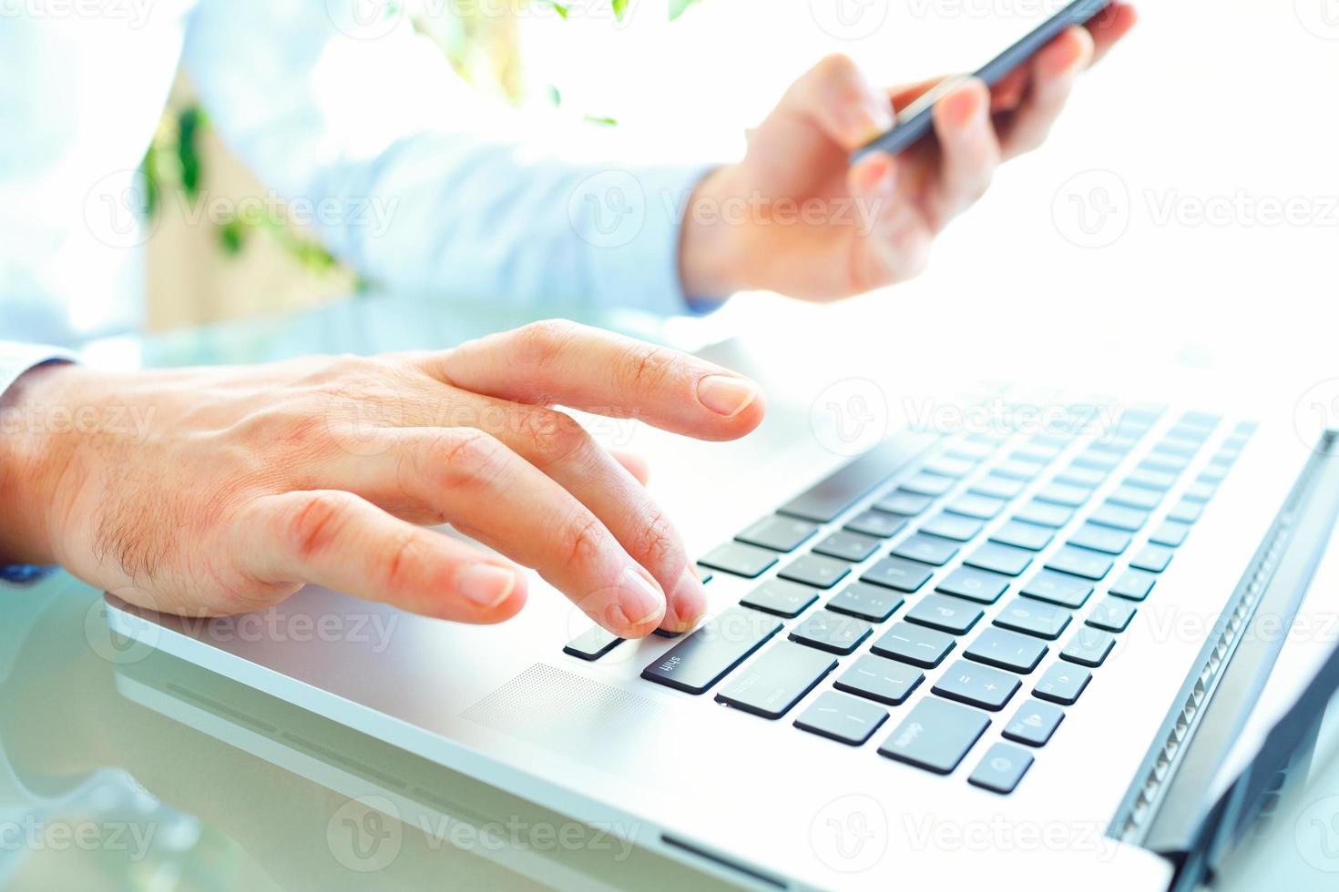 Men office worker typing on the keyboard and using smartphone photo