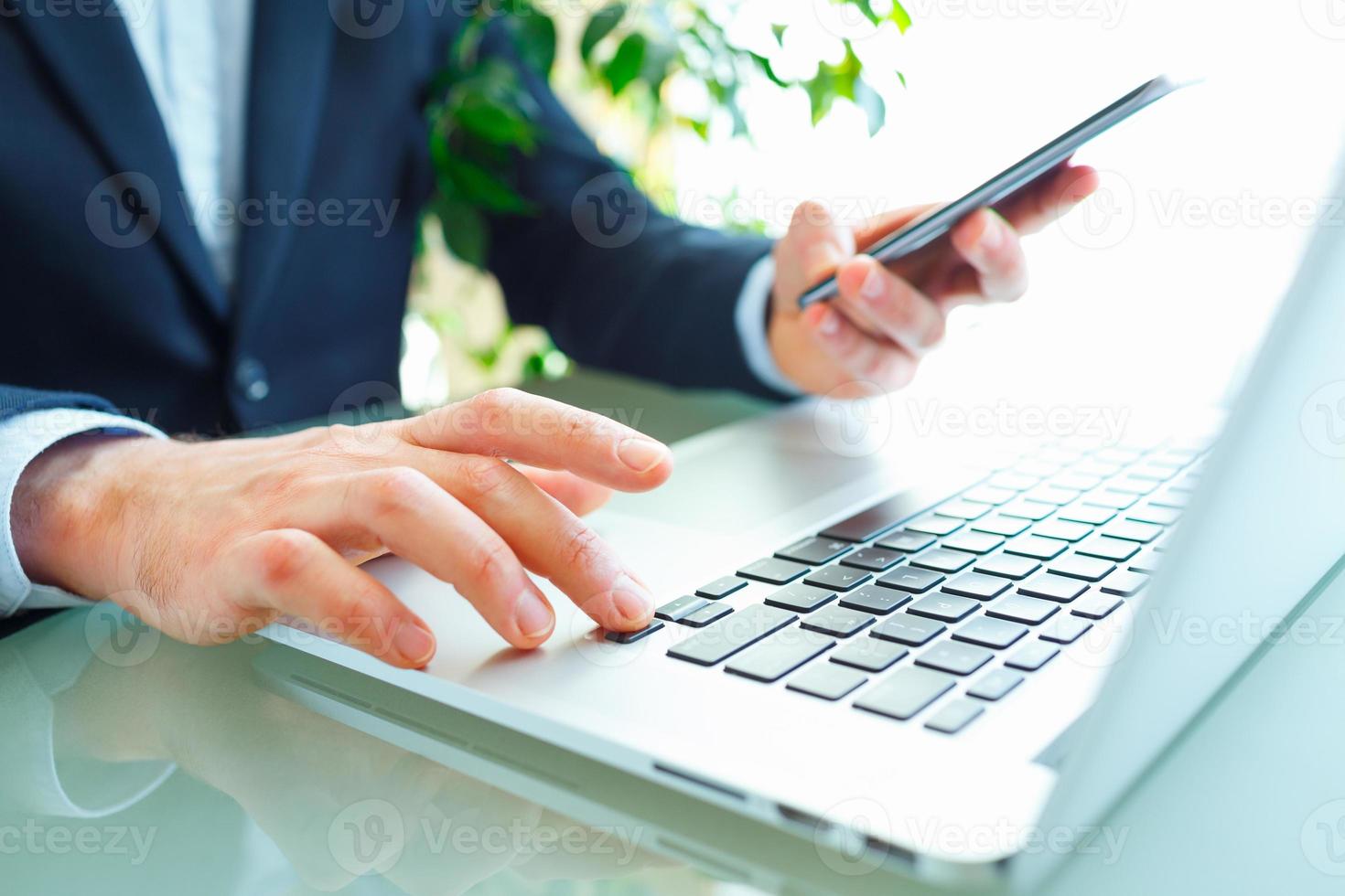 Men office worker typing on the keyboard and using smartphone photo