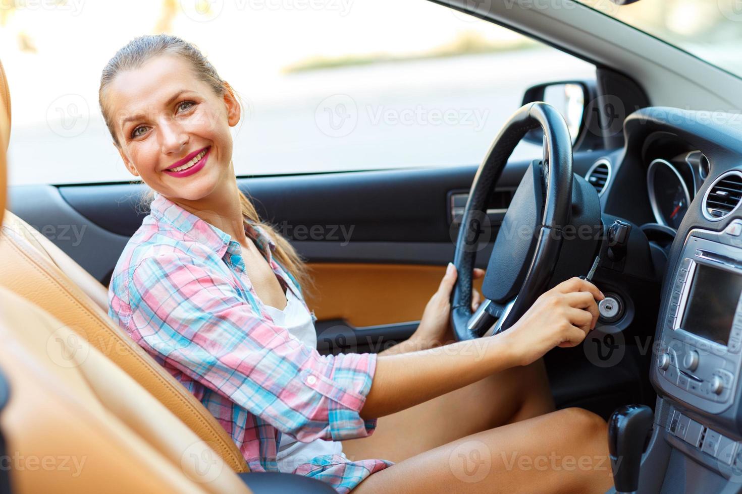 mujer sentado en un convertible y es yendo a comienzo el motor - el concepto de comprando un usado coche o un alquiler coche foto