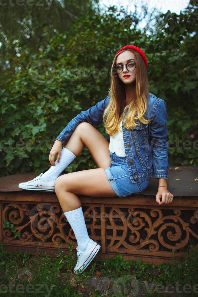 Beautiful girl posing against the backdrop of the green grass and trees photo