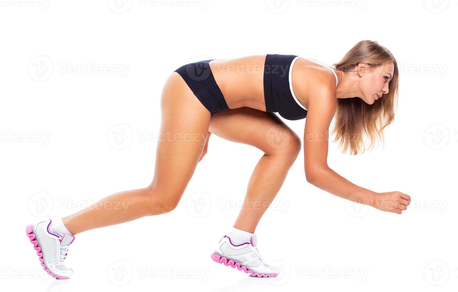 Young sports girl does exercises on a white photo