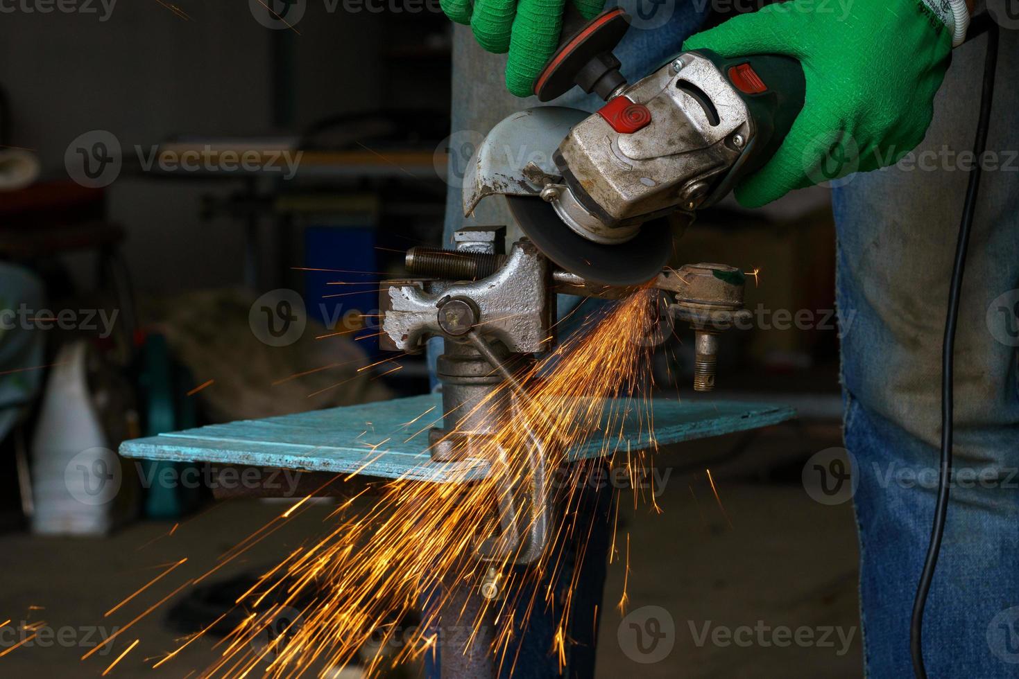 Worker with angular grinding machine is cutting the metal photo