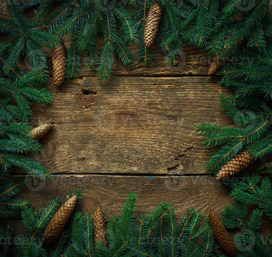 Christmas tree branches with cones on wooden texture ready for your design photo