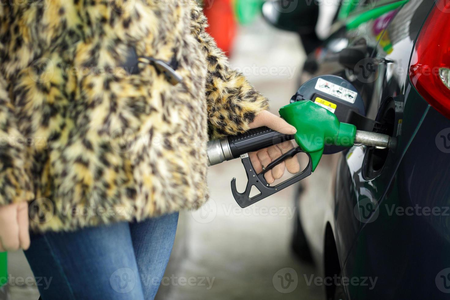 Woman fills petrol into her car at a gas station in winter photo