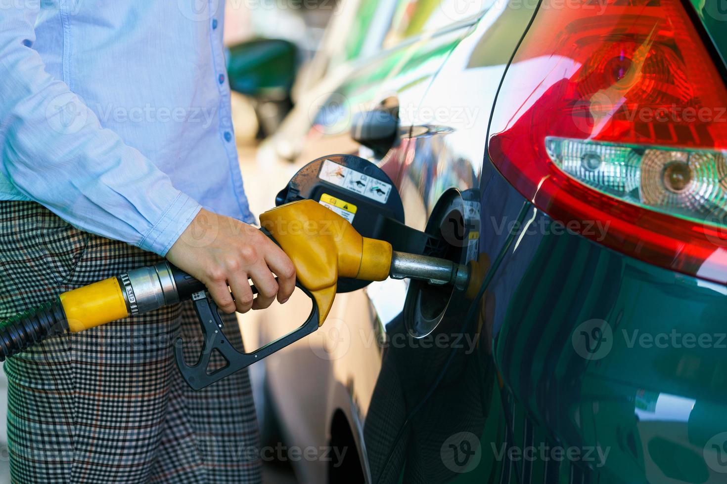 Woman fills petrol into the car at a gas station photo