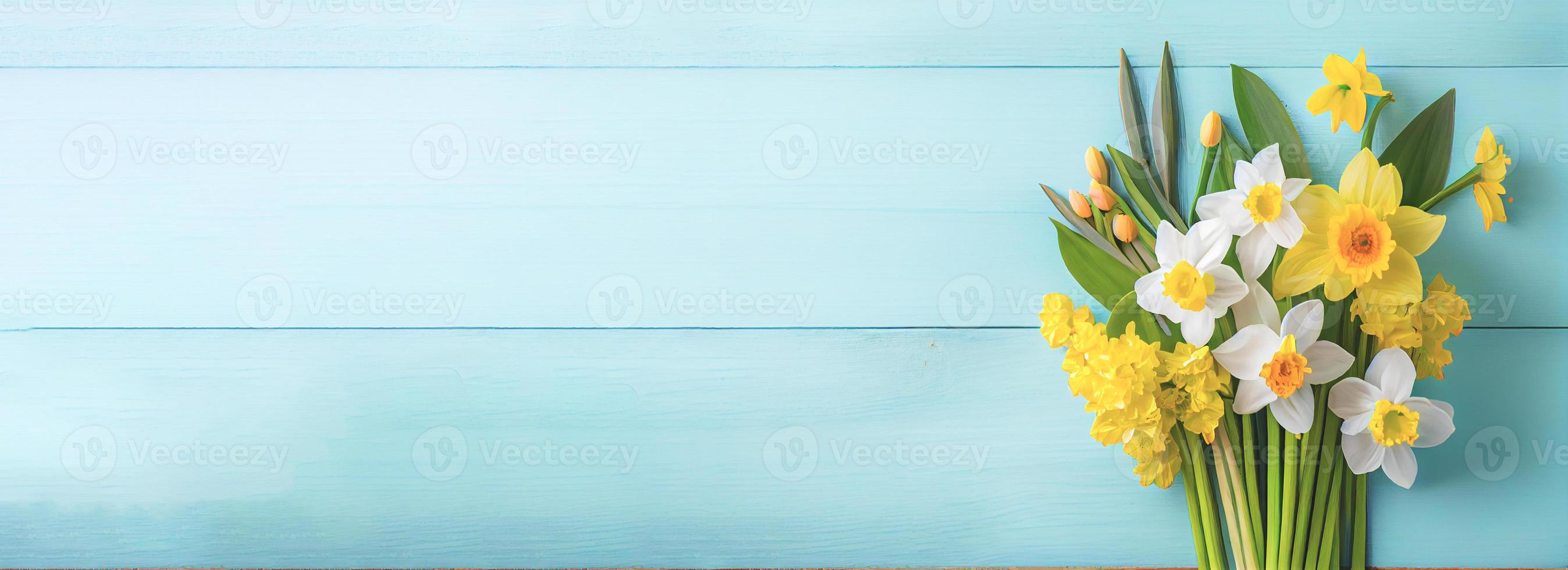 Spring easter background with top view of daffodils bouquet on light blue wooden table with copy space photo