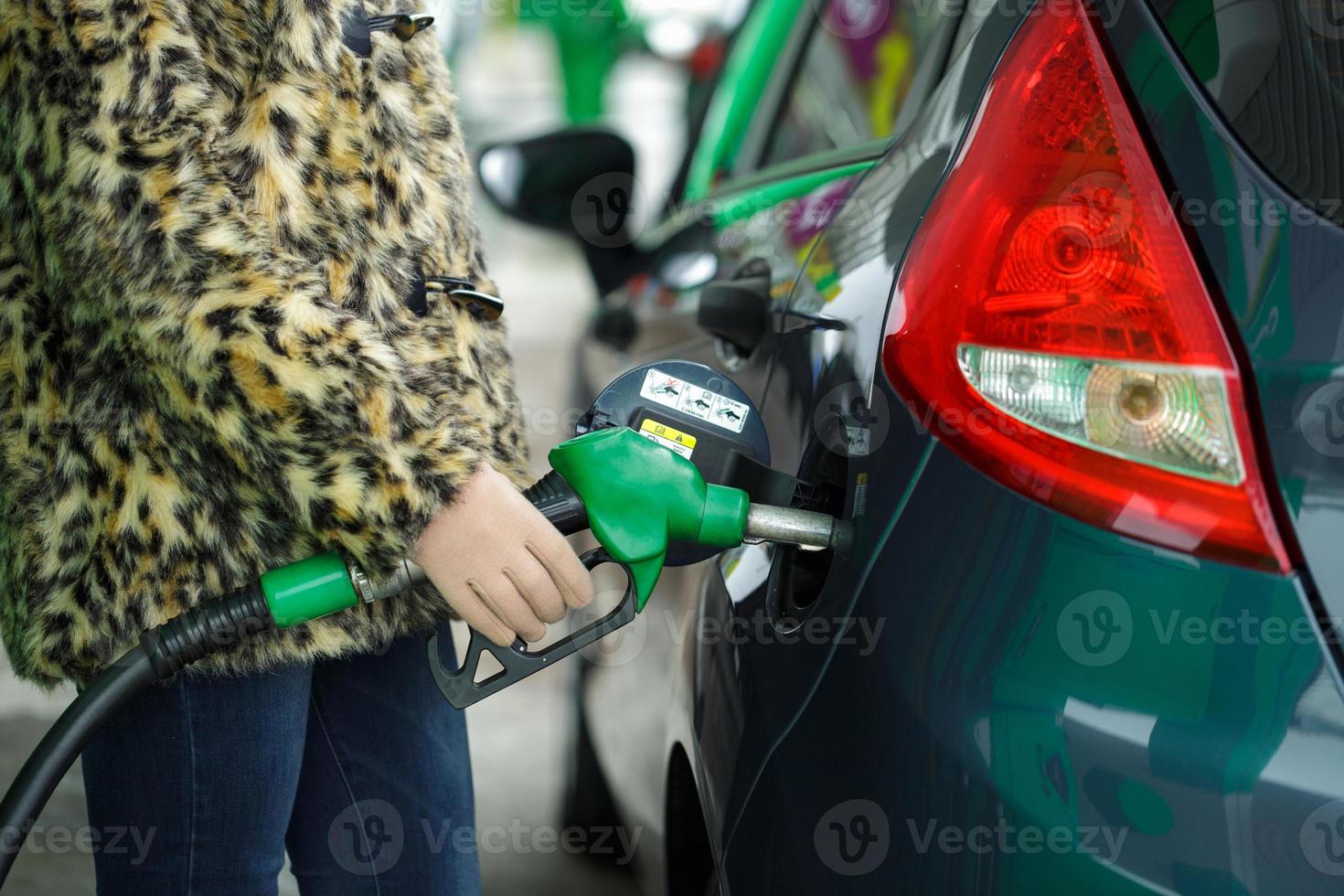 Woman fills petrol into her car at a gas station in winter photo