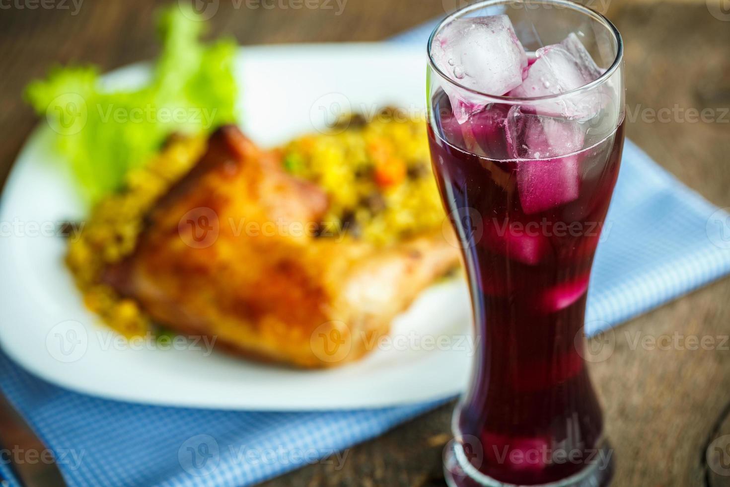 Dishes from chicken thigh with rice and lettuce and a glass of juice with ice photo