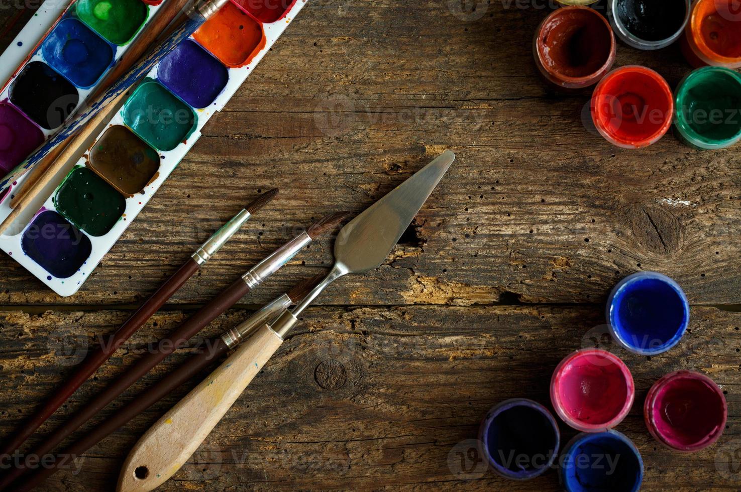 Watercolors and paint brush on wooden background photo