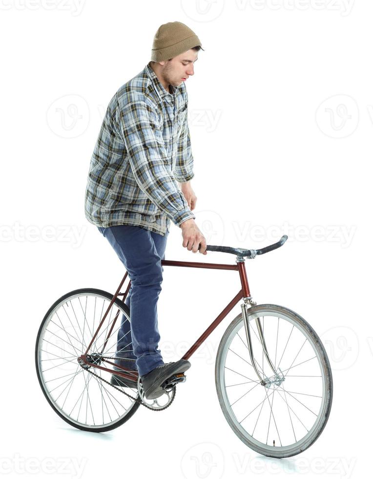 Young man doing tricks on fixed gear bicycle on a white photo