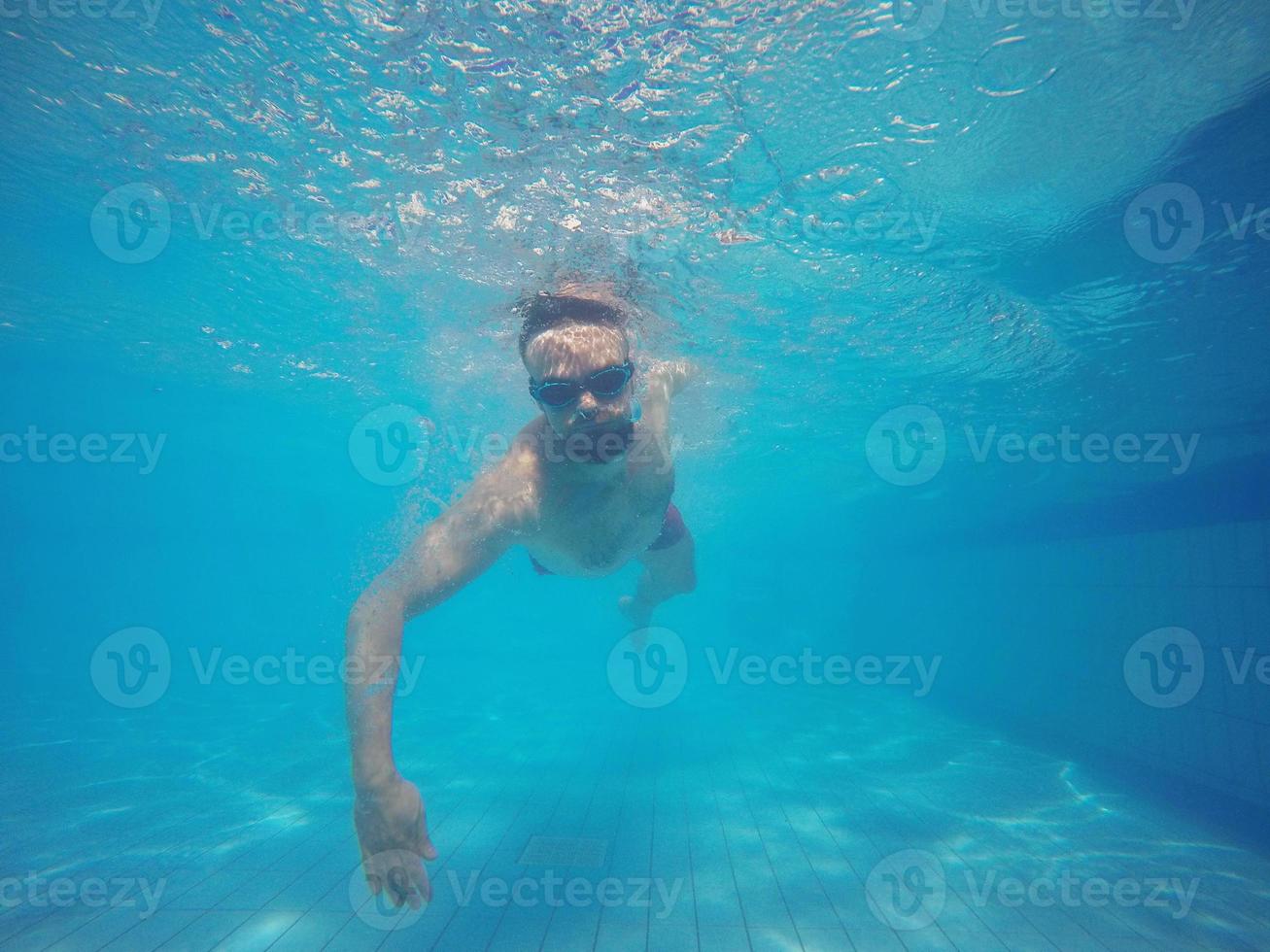 barba hombre con lentes nadando debajo agua en el piscina foto