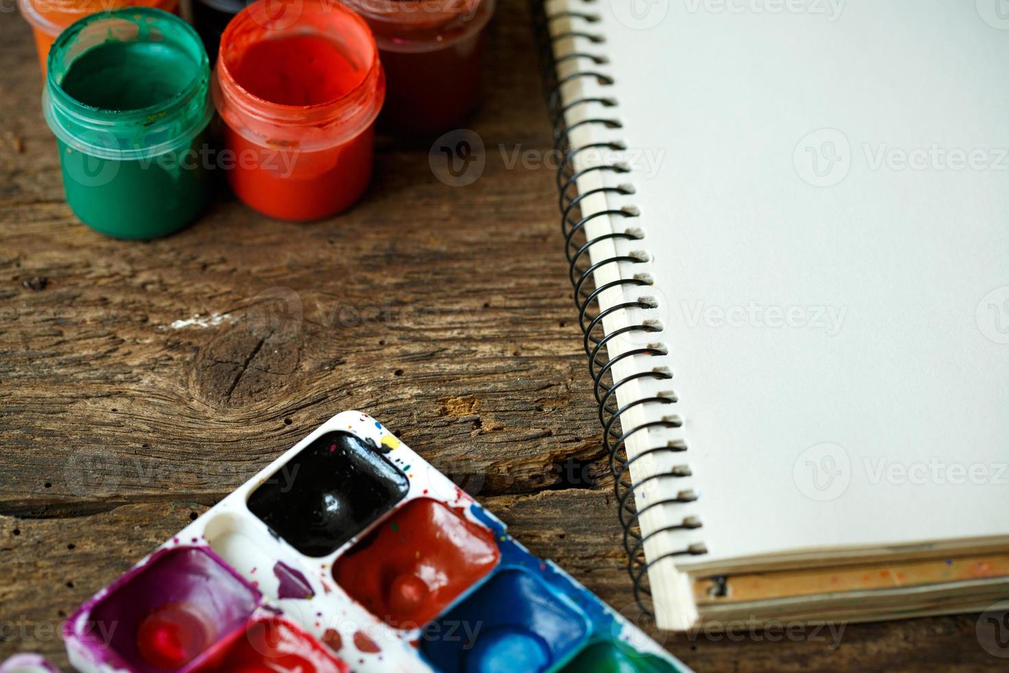 Paper, watercolors and paint brush on wooden background photo