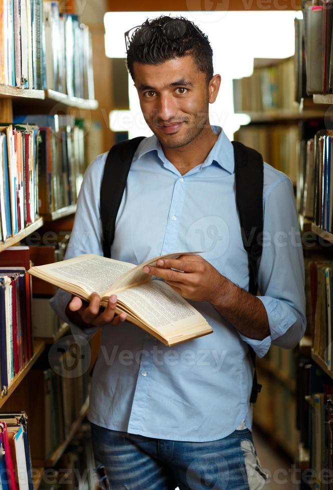 Student reading book between the shelves in the library photo