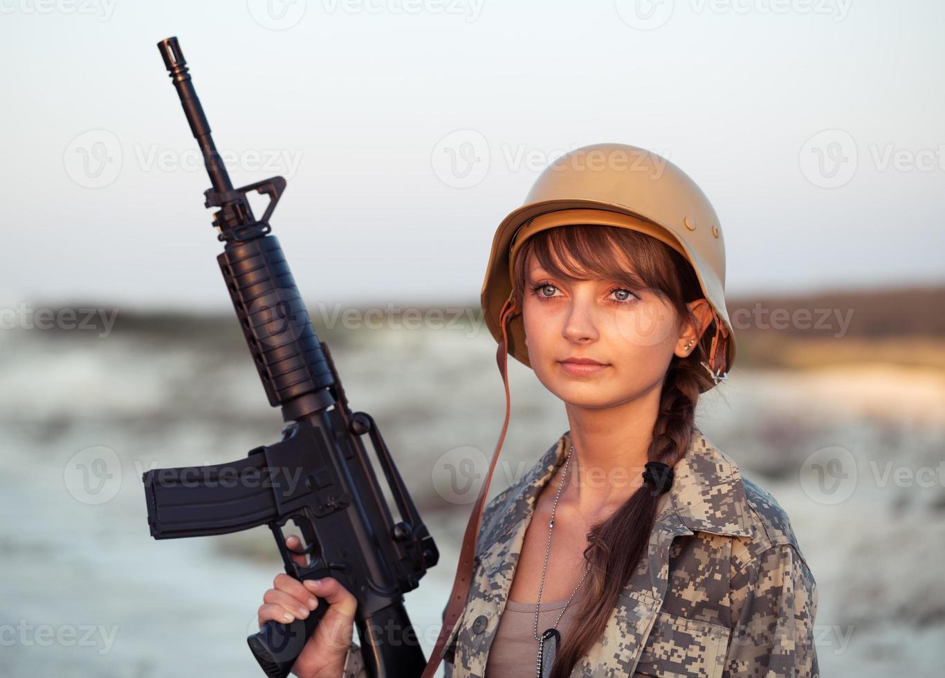 joven hembra soldado vestido en un camuflaje con un pistola en el al aire libre foto