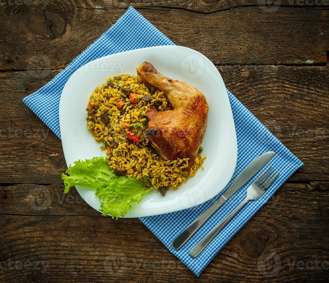 Delicious dish of chicken thigh with rice and salad leaves photo