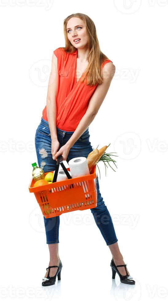 Happy young woman holding a basket full of healthy food on white. Shopping photo
