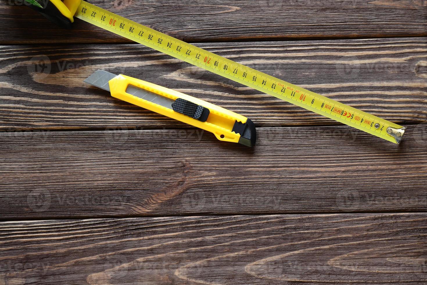 Tape measure, building knife, screw on wooden table, copy space photo