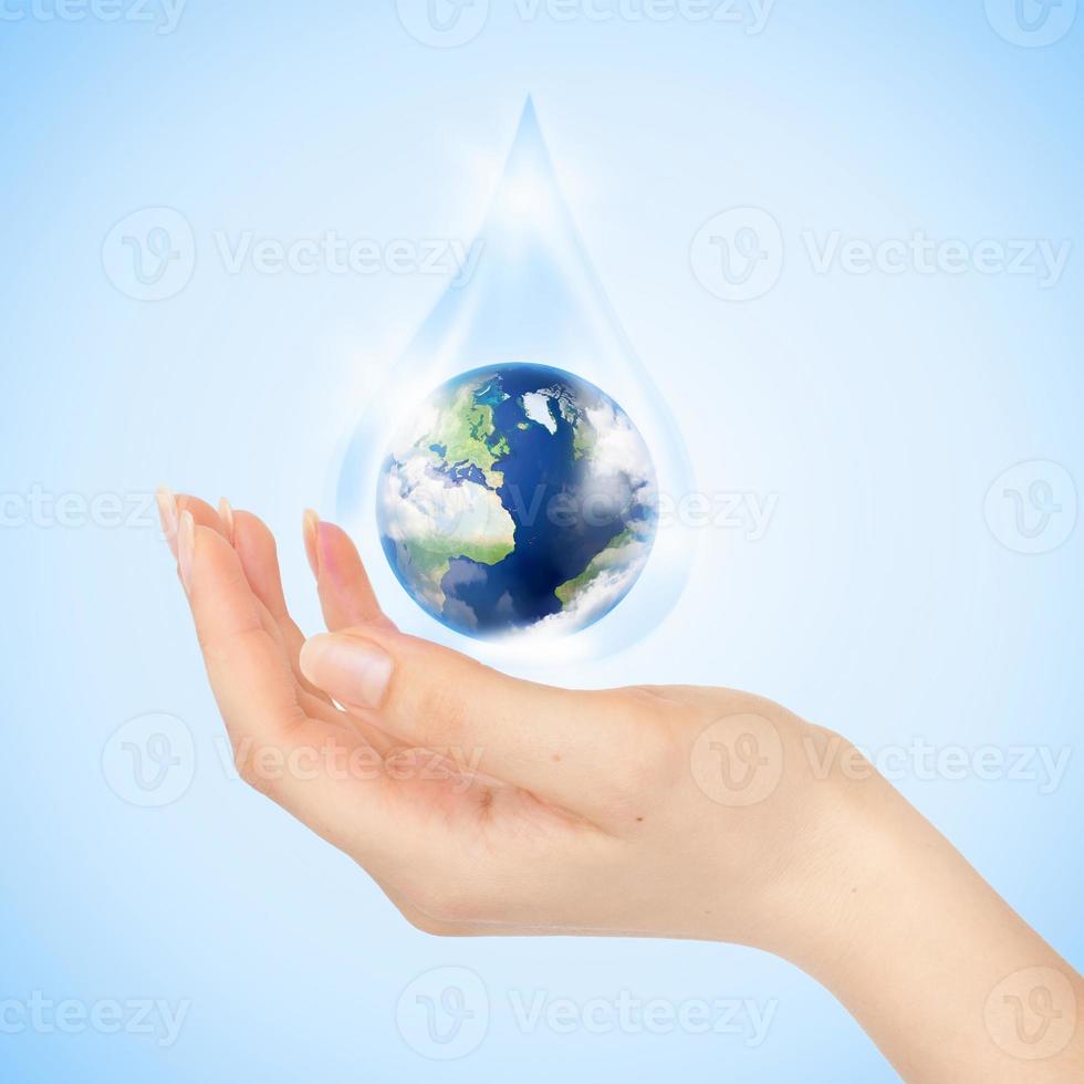 Drop of water with Earth inside and hand photo