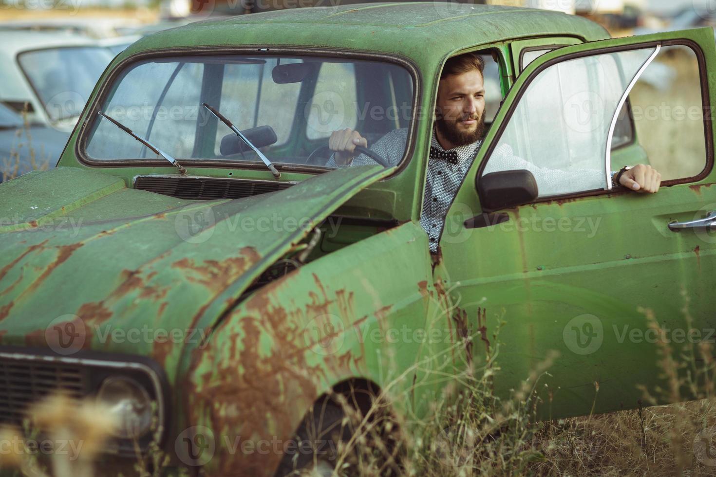 joven hermoso elegante hombre, vistiendo camisa y corbata de moño con antiguo carros foto