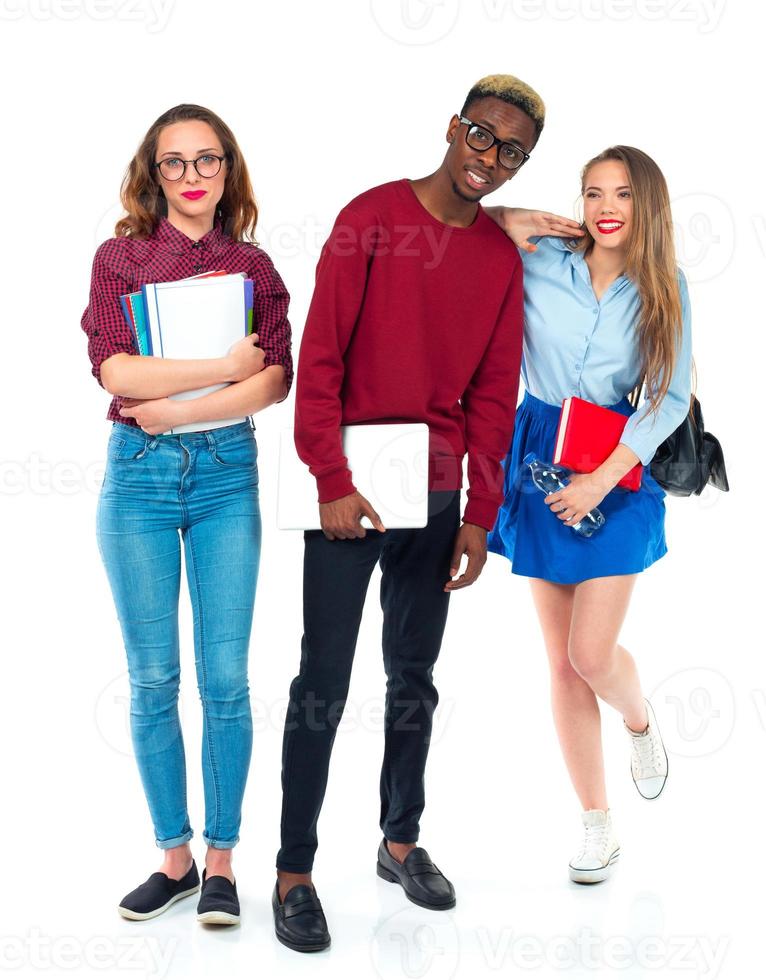 Happy students standing and smiling with books, laptop and bags isolated on white photo