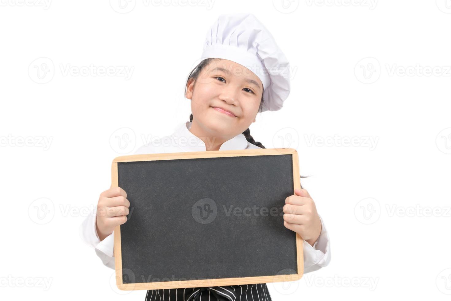 pequeño asiático niña cocinero en uniforme cocinar participación pizarra para en poner texto o menú, aislado foto