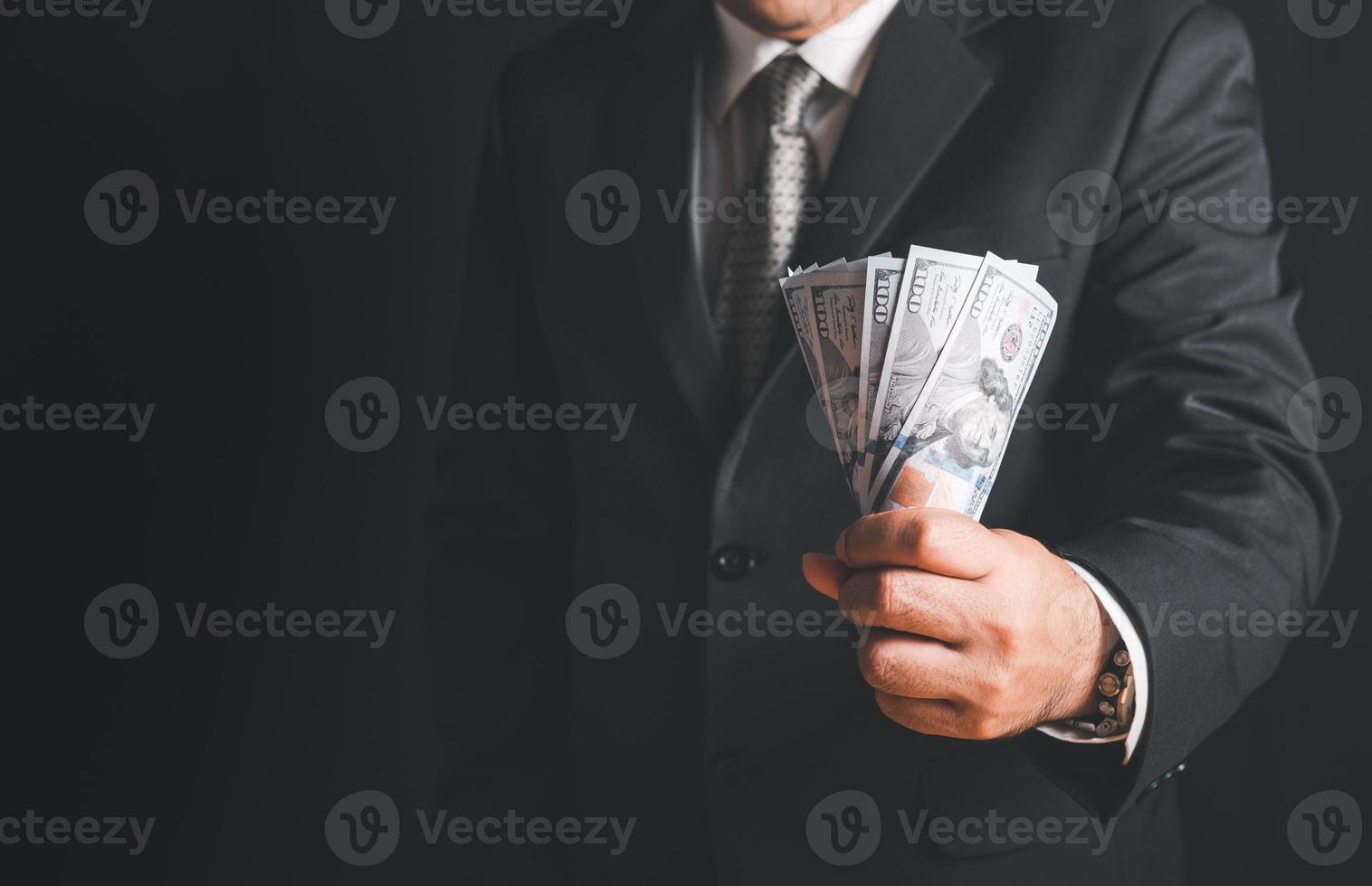 Businessman hand grabbing money, US dollar USD bills on black background, photo
