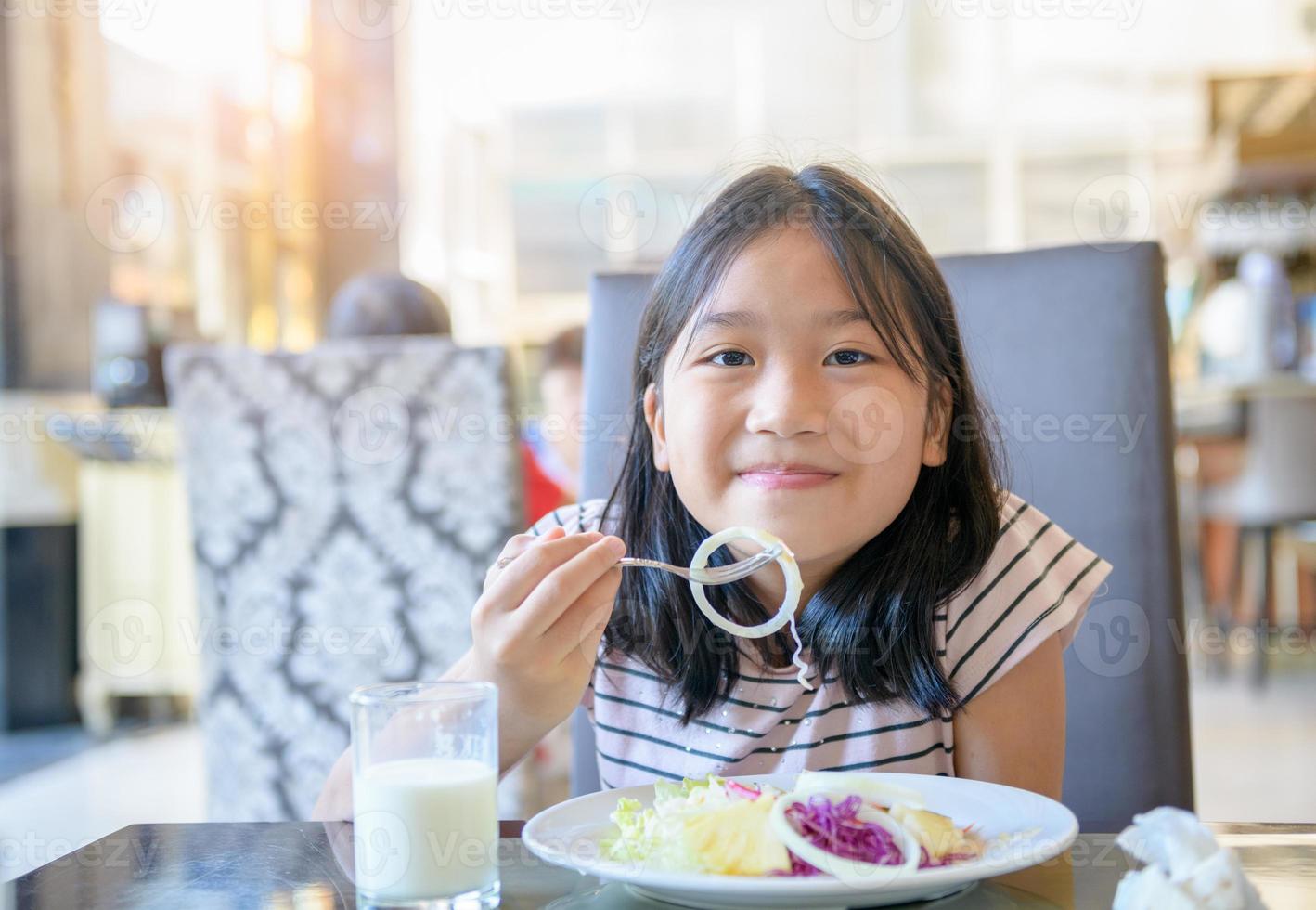 Happy Little girl eat onion in salad with  fresh milk on morning, Healthy food photo