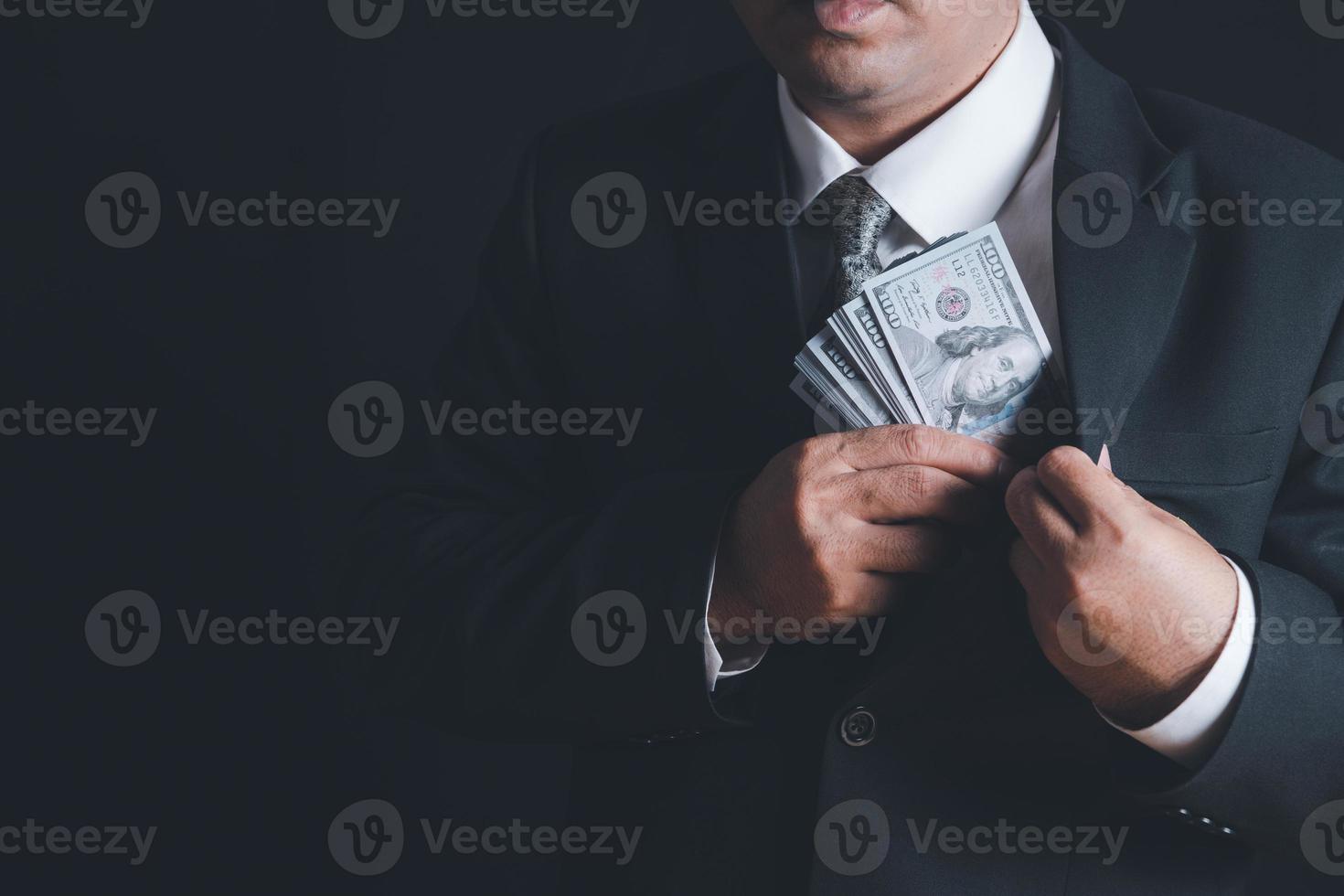 Man putting bribe money into pocket on black background, photo