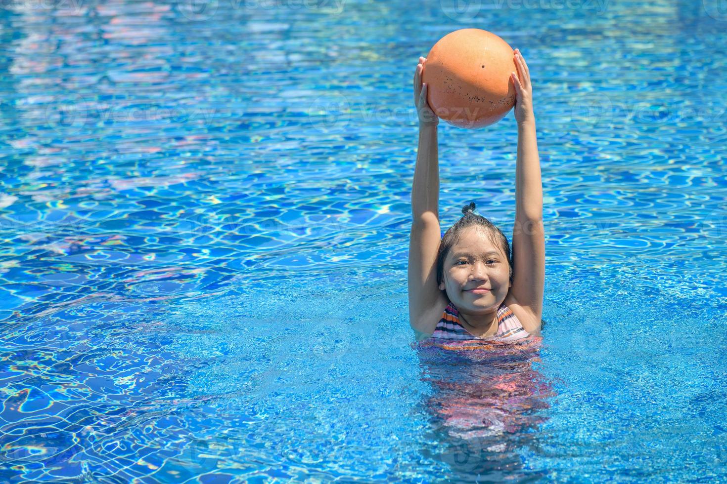 Happy girl playing ball in swimming pool, recreation concept photo