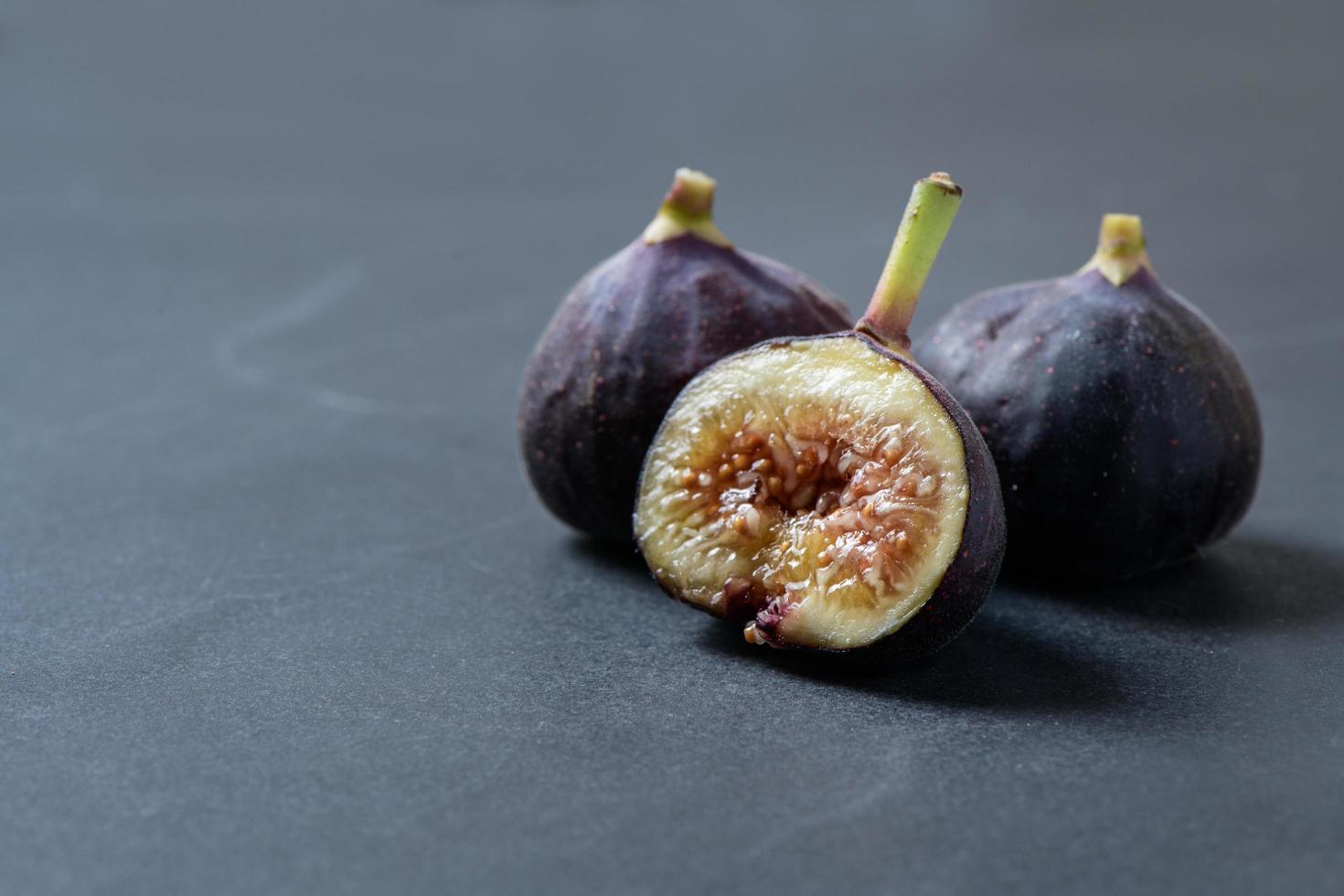 Slices fresh purple fig fruit on black background, photo