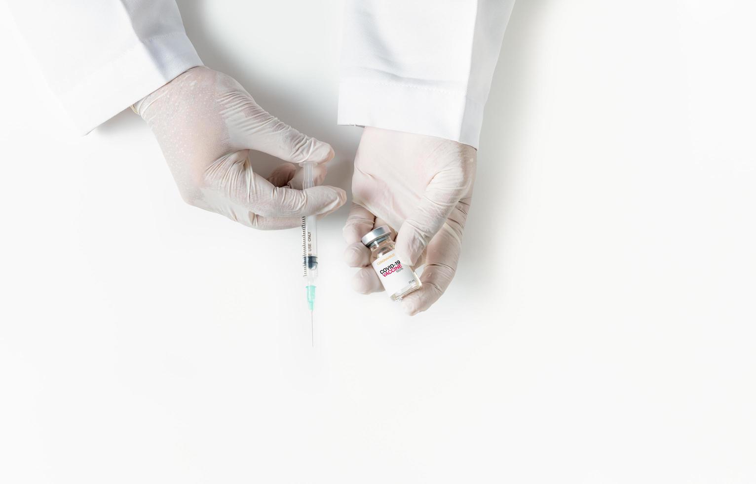 Doctor or scientist hand in white gloves holding flu, measles, coronavirus vaccine shot photo