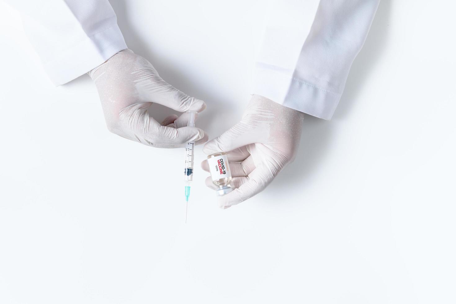 Doctor or scientist hand in white gloves holding flu, measles, coronavirus vaccine shot photo