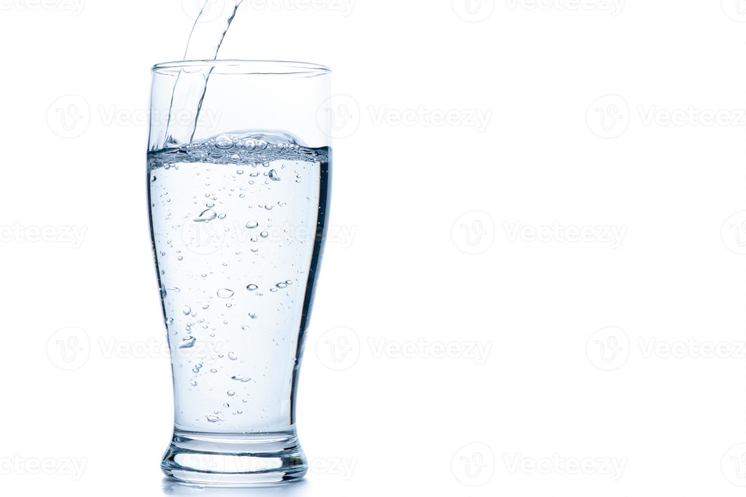 Water pouring into the clear Pilsner glass isolated on white photo