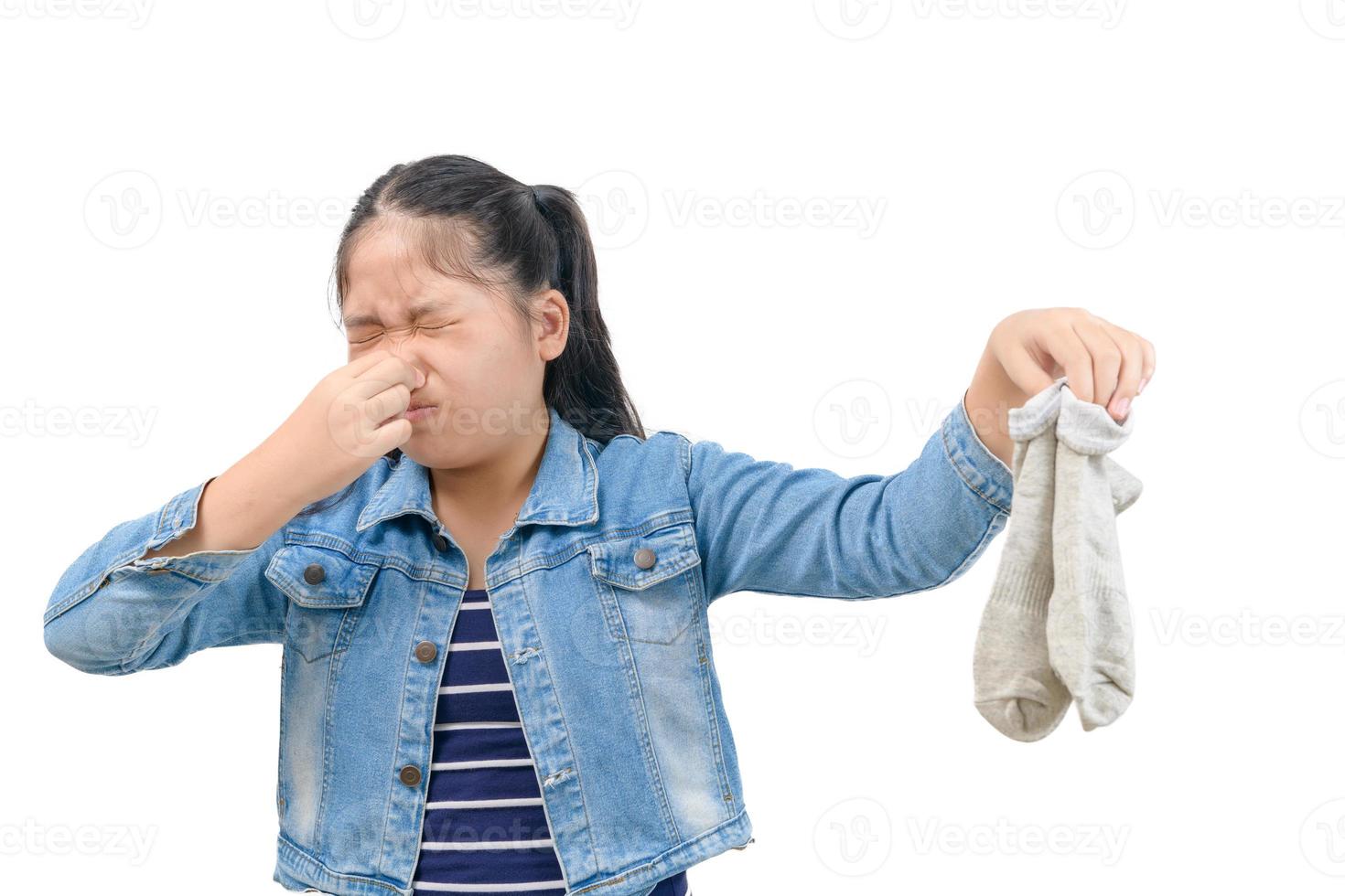 Asian little girl holding her nose because of a bad smell of a socks isolated on white photo
