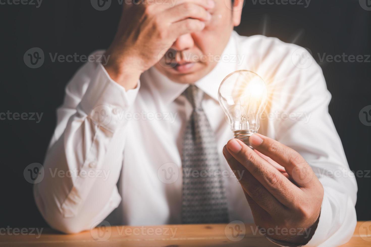 A business man stressed and hold light bulb in hand photo